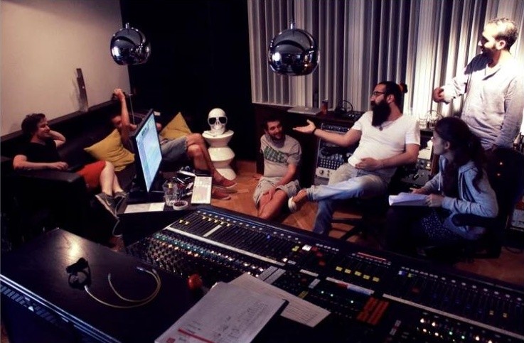 The band relaxing around the mixing desk between takes