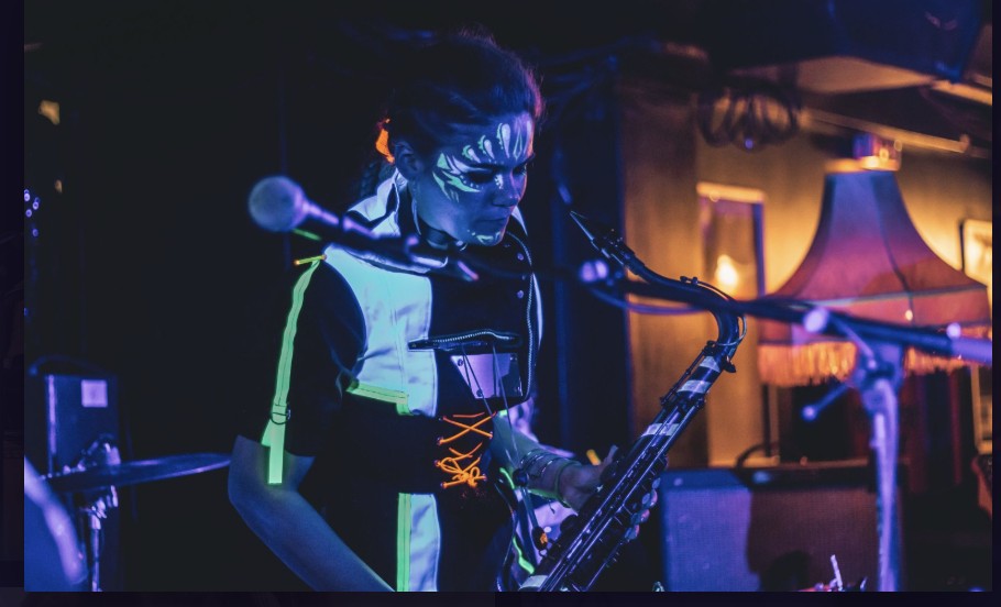 Lety ElNaggar performing saxophone under UV face paint and blue light